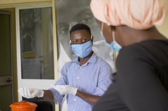 Abdoulaye learns the correct method of wearing a mask and gloves from Dr. Fatoumata Sanassy Keita. Photo: IOM Guinea 2020