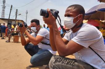 Mark capturing pictures at a community theatre performance in Benin City during a photography training for returned migrants. © IOM 2021/Elijah Elaigwu