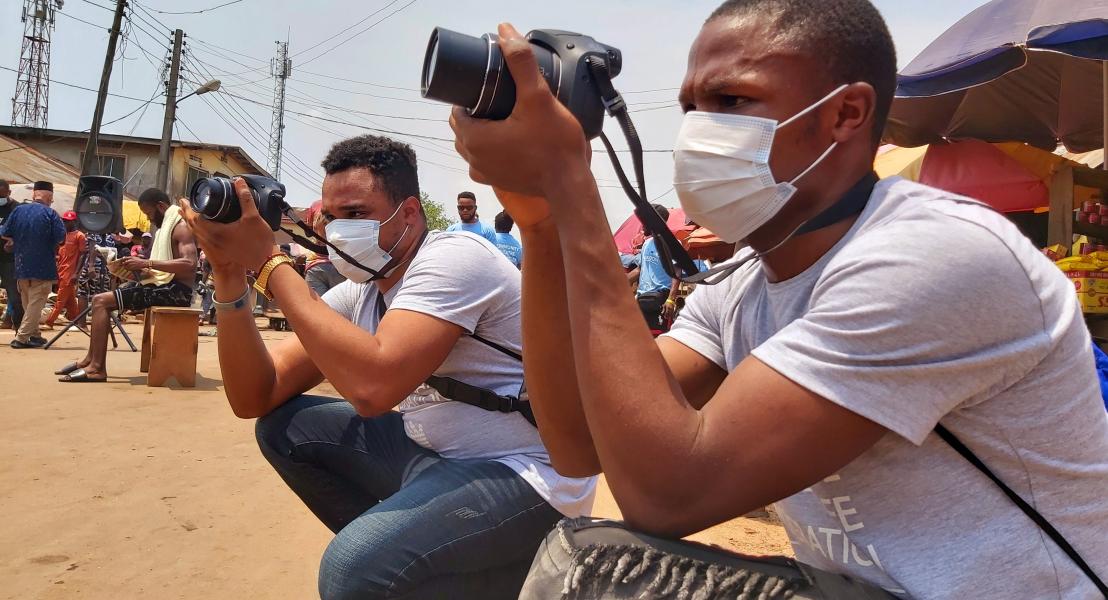 Mark capturing pictures at a community theatre performance in Benin City during a photography training for returned migrants. © IOM 2021/Elijah Elaigwu